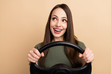 Photo of amazed young charming woman driving automobile distracted from the road and look in mirror isolated over beige color background