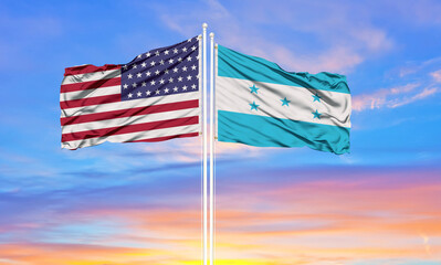 United States and Honduras two flags on flagpoles and blue cloudy sky . Diplomacy concept, international relations