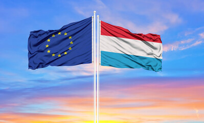 European Union and Luxembourg two flags on flagpoles and blue cloudy sky . Diplomacy concept, international relations