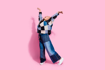 Full size photo of positive carefree girl dressed jeans pullover oversize pants raising hands like wings isolated on pink color background