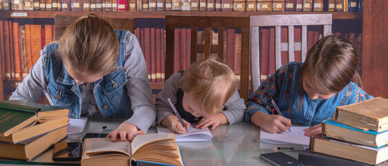 Funny portrait of little scientists studying and read books in the library. Humorous photo. Horizontal image.