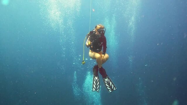 Woman, swimming and scuba diving in ocean to explore underwater and tropical holiday or eco vacation. Person or diver gas cylinder and bubbles to search deep blue water, sea life and nature adventure