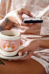 Woman drinking tea and texting on smartphone. Cozy winter weekend morning.