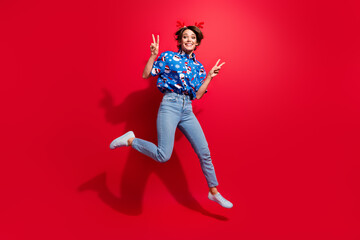 Full body photo of jump overjoyed young lady showing double v sign winter holidays shopping season start isolated on red color background