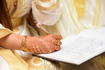 Bride hand with a pen signing wedding license.