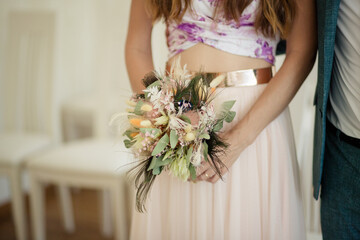 Braut hält modernen Brautstrauß mit Trockenblumen Pfauenfeder und Eukalyptus - 690251868