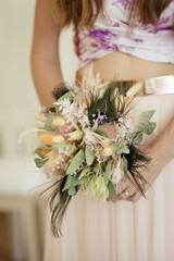 Braut hält modernen Brautstrauß mit Trockenblumen Pfauenfeder und Eukalyptus - 690252099