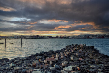 An old ruined pier in the bay and a view of the evening city. Portland. USA. Maine. View of the bay and evening Portland. State of Maine.
