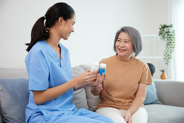 caregiver or nurse giving and holding medicine pills bottle to senior woman on sofa