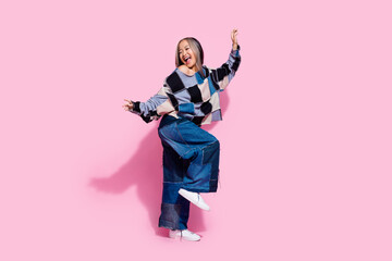 Full size photo of good mood girl dressed jeans pullover oversize pants dancing look at sale empty space isolated on pink color background