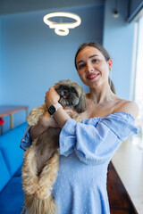 Brunette CEO with shih tzu smiling in business company. Young female with smilling expression standing in modern company office