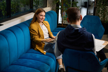Man and woman are sitting with work documents on sofa