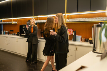 Young women enjoy hot beverages and talk about recent news and trends in the industry. Female...
