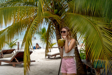 Kobieta pije kokosa pod palmą