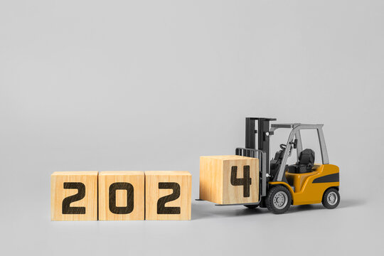 2024 happy new year background. new year industrial concept, forklift carrying box to complete 2024 text isolated on grey background.