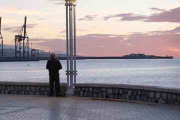 Paseo marítmo de Málaga, amanecer sobre el mar, hombre tercera edad visto de espaldas, mirando...
