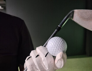 Golfer in golf gloves with iron club and equipment golf ball