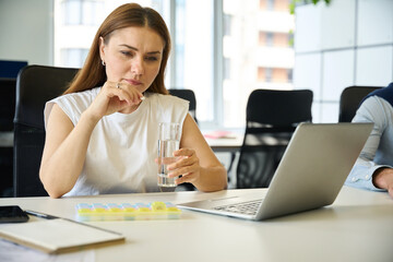 Woman holds a glass of water and tablet in her hands