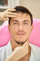 Obraz premium Specialist esthetician examines the face of a brown-haired man