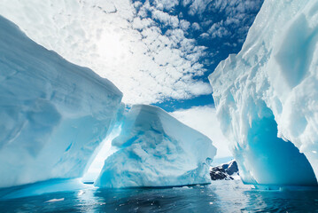 An iceberg floats majestically in the polar regions, a testament to the raw power and beauty of nature. Its icy blue hues contrast with the surrounding ocean.