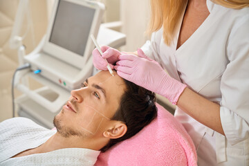 Fototapeta premium Specialist makes marks on the patients face