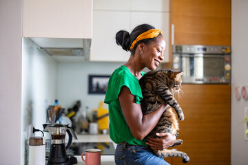 Smiling woman holding her cat at home
 - obrazy, fototapety, plakaty