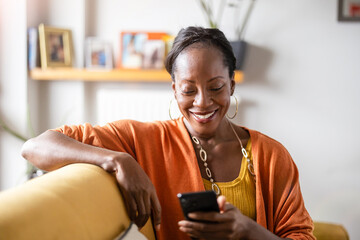 Mature woman using mobile phone while relaxing on sofa at home
