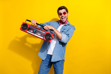 Portrait of positive man with stubble dressed denim shirt sunglass holding boombox at party...