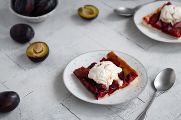 Piece of Fresh baked German Plum cake Zwetschgenkuchen with a scoop of ice cream in a rustic style. Healthy autumn food.