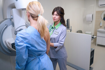 Experienced mammographer preparing woman for digital mammogram in clinic