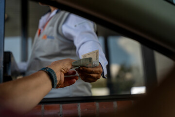 Male paying with cash at a toll booth in Colombia, South America.
