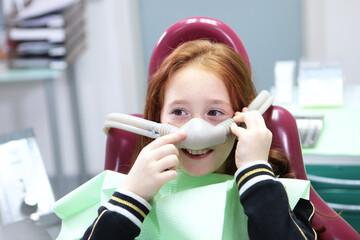 Little girl with sedation mask. Treatment of children's teeth with nitrous oxide. Children's...