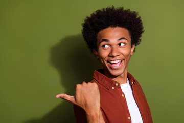 Photo of good mood cheerful man with afro hair dressed brown shirt look directing at sale empty space isolated on khaki color background