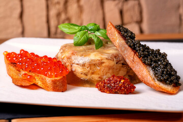 Sturgeon aspic, two slices of fried bread, and red and black caviar. Spicy seasoning on a white...
