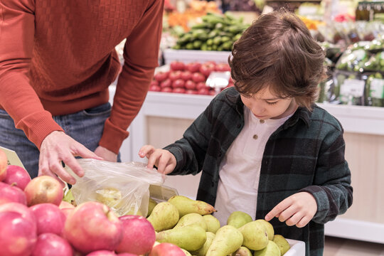 This moment at the grocery store, where a child engages with choosing pears, captures the essence of parental influence on a child's dietary preferences and the subtle teachings of a healthy lifestyle