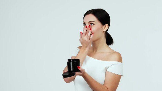 Portrait of a charismatic young woman using face creams. Concept of fresh moisturized skin, beautiful cosmetic face, happy healthy model. A young brunette takes care of her skin.