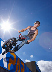 Bike, jump and man on ramp for sport performance, ride or training for summer event at park with...