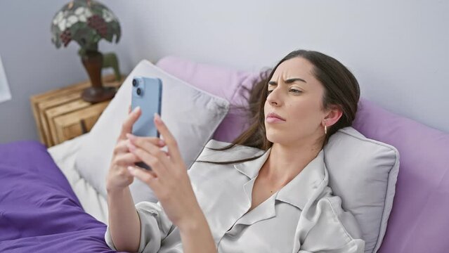 Young beautiful hispanic woman lying on bed finishing using smartphone to sleep at bedroom