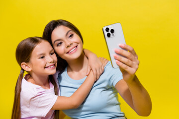 Photo of two cute girls best friends make selfie on cell smart device isolated over vibrant color...
