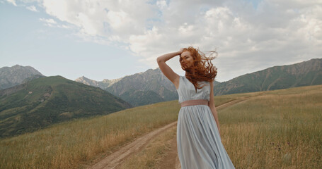 Happy young woman on the mountain road on the sunset or sunrise in summer nature. Pretty young...