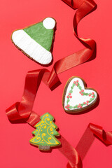 Delicious Christmas gingerbread cookies and a satin red ribbon on a red background. Top view.