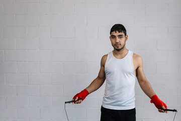 Horizontal photo man young adult jumping rope, with red boxing gloves in hands. Sports concept.