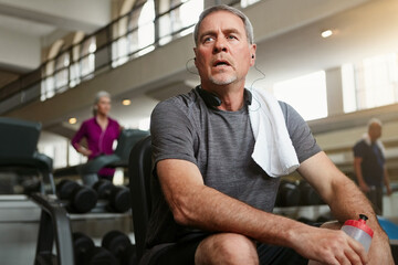 Fitness, break and tired senior man at a gym with water after training, exercise or challenge. Sports, fatigue and elderly male person with liquid for hydration, recovery or resting from workout - Powered by Adobe