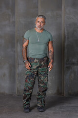 A soldier in camouflage, a soldier stands against the wall.A mature male bodybuilder in a military...