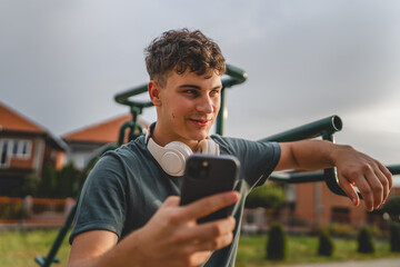 man young male stand outdoor open training park gym use mobile phone