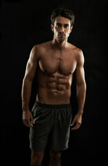 Fototapeta na wymiar Topless, black background or portrait of man with six pack, strong abs or stomach in studio. Fitness model, cool or ripped male person with healthy body, dark shadow or abdomen muscle for wellness