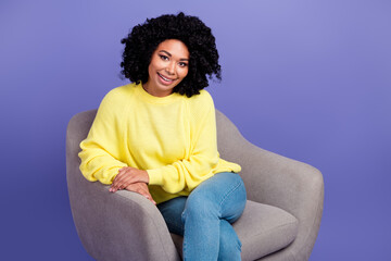 Photo of positive pleasant girl with chevelure dressed yellow pullower sit on armchair on interview isolated on purple color background