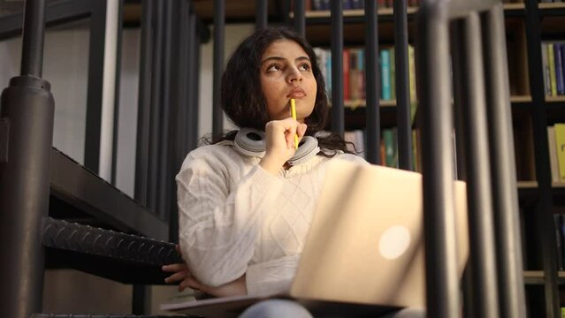 Portrait of pretty doubtful creative young woman student searching inspiration thinks questioningly about difficult choice choose imagine plan in mind has doubts create idea at university library