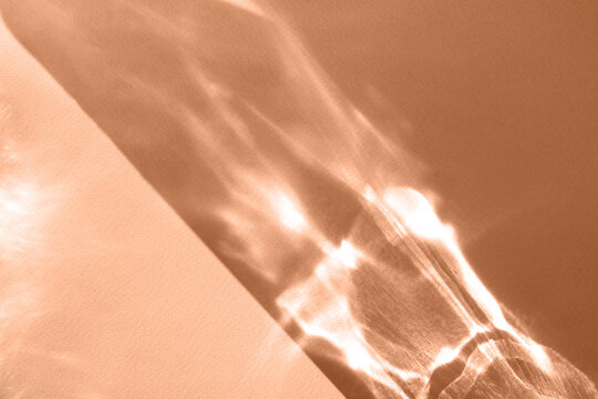 Abstract shadow sun glare from glass, empty background composition for product presentation. The background is beige. Showcase Nude Studio Minimal. Beautiful trendy peach fuzz color background.