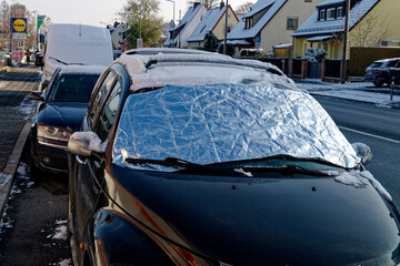 Windshield of a parked car covered with protective film in winter
